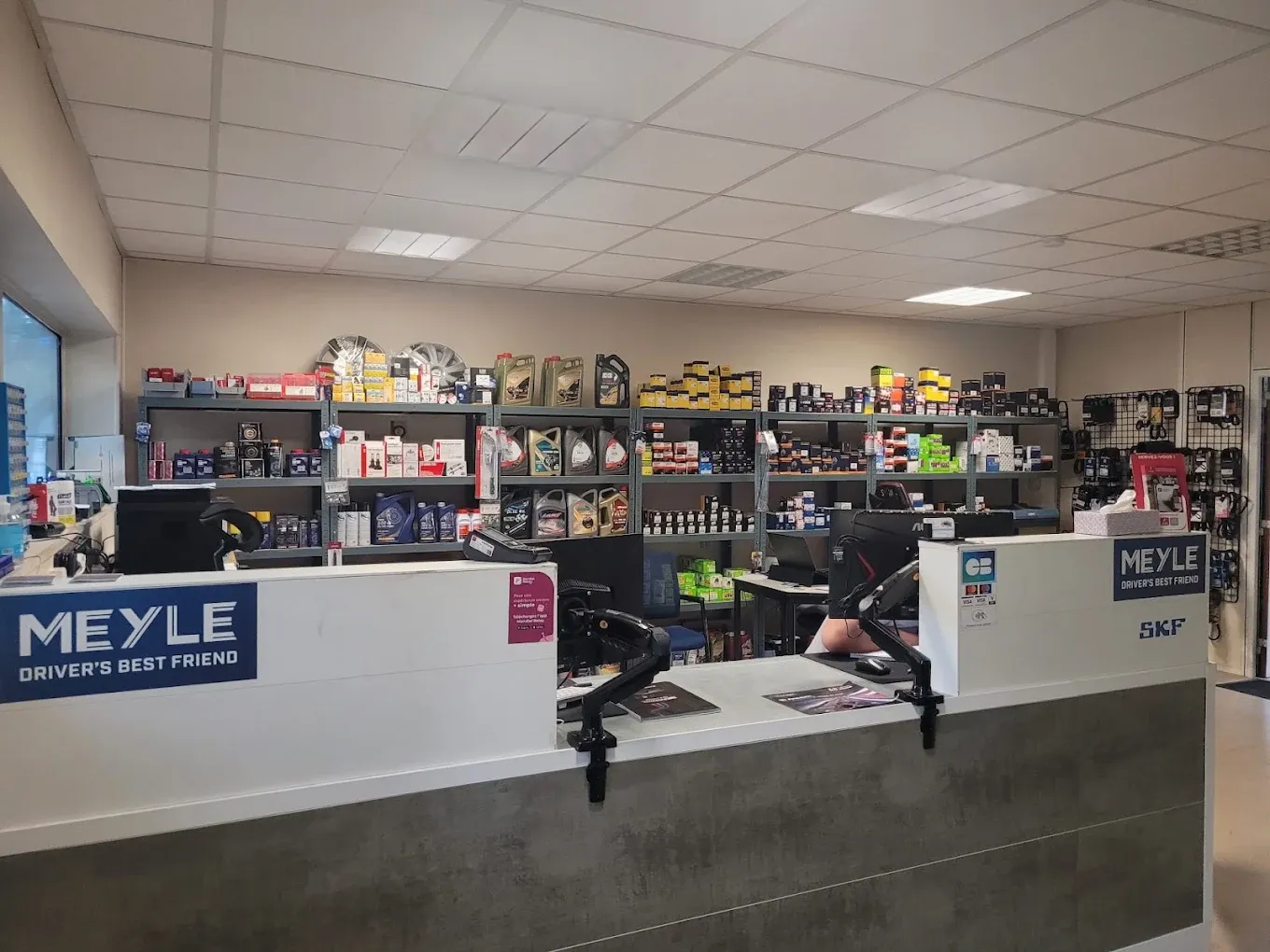 Le comptoir de la boutique Perfect Parts Auto à Taverny, rayons d'huiles, filtres et pièces en arrière-plan